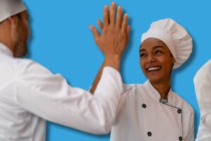 une photo de deux cuisiniers se tapant dans la main après avoir appris les 10 compétences clés en restauration