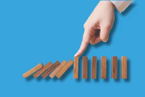 une main et des dominos qui tombent, la main vient stopper la chute des dominos pour illustrer qu'un geste peut éviter la chute.