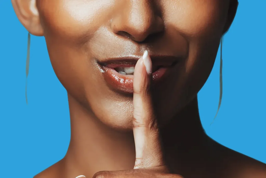 une femme qui fait le signe "chut" avec sa bouche et son doigt pour illustrer l'idée de garder le secret